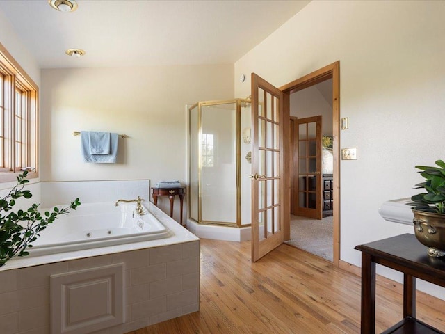 full bath featuring a shower stall, wood finished floors, a whirlpool tub, and french doors