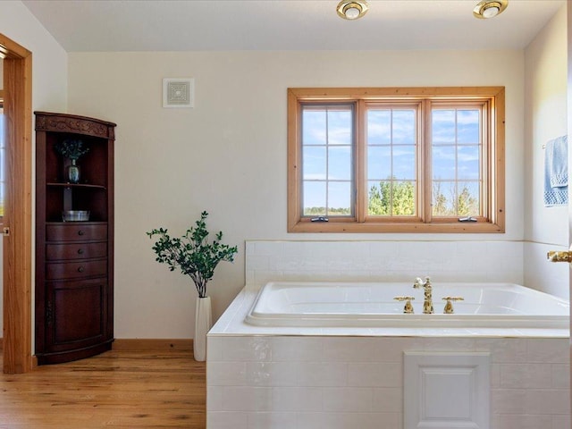 bathroom featuring wood finished floors, a garden tub, and baseboards
