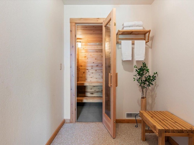 relaxing sauna featuring carpet flooring and baseboards