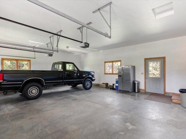 garage with a garage door opener, stainless steel fridge, and baseboards