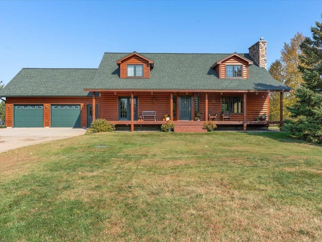 log-style house with covered porch, a chimney, an attached garage, a front lawn, and driveway