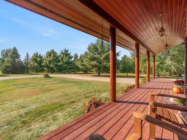 wooden deck with a lawn and view of wooded area
