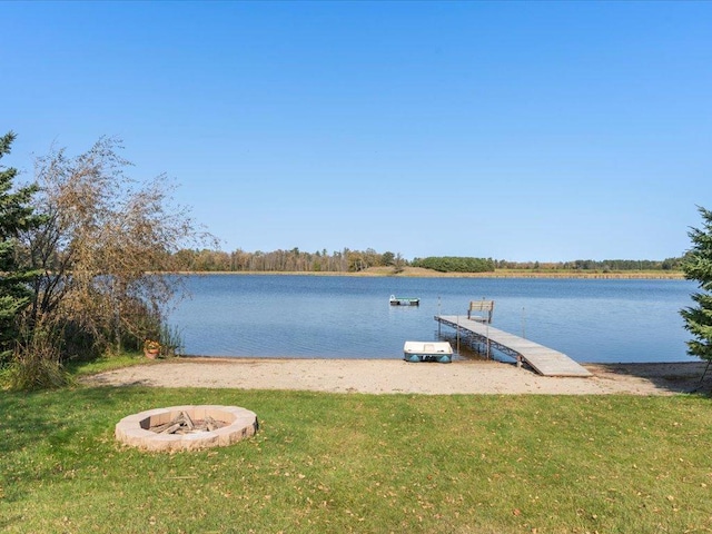 dock area featuring a fire pit, a water view, and a lawn