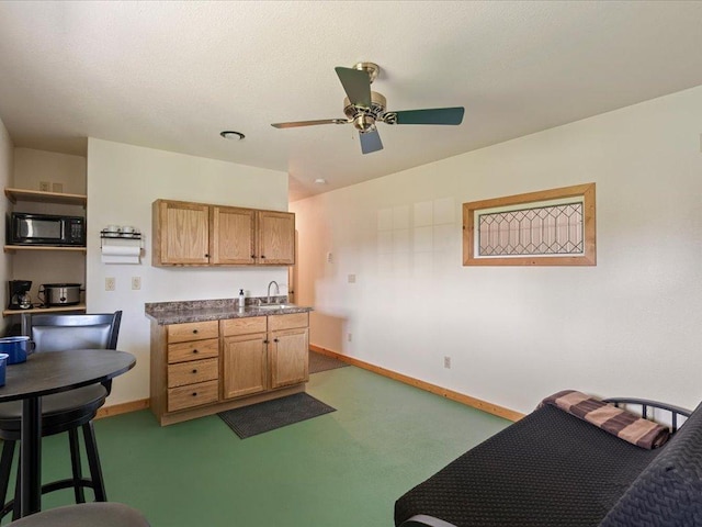 kitchen featuring black microwave, a sink, ceiling fan, and baseboards