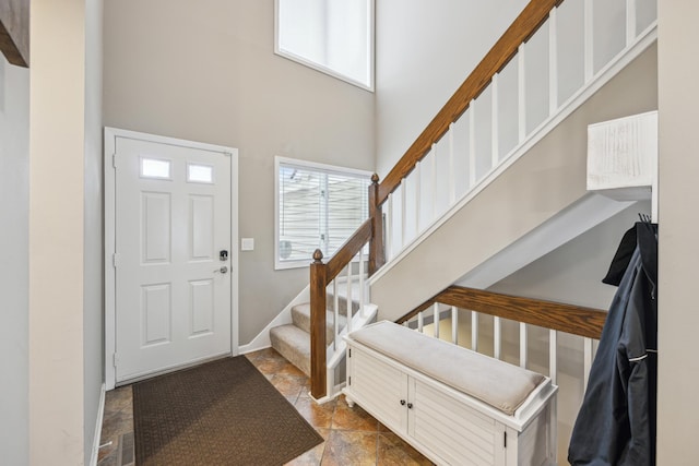 entryway featuring healthy amount of natural light, a high ceiling, stairs, and baseboards
