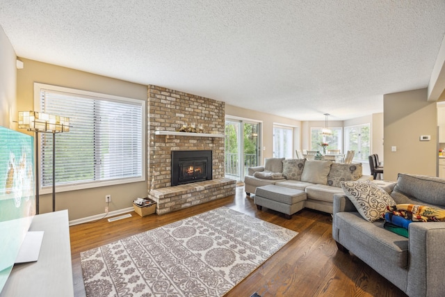 living area with a textured ceiling, dark wood-type flooring, a fireplace, and baseboards