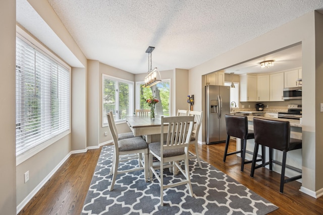dining room with dark wood-style flooring, a textured ceiling, and baseboards
