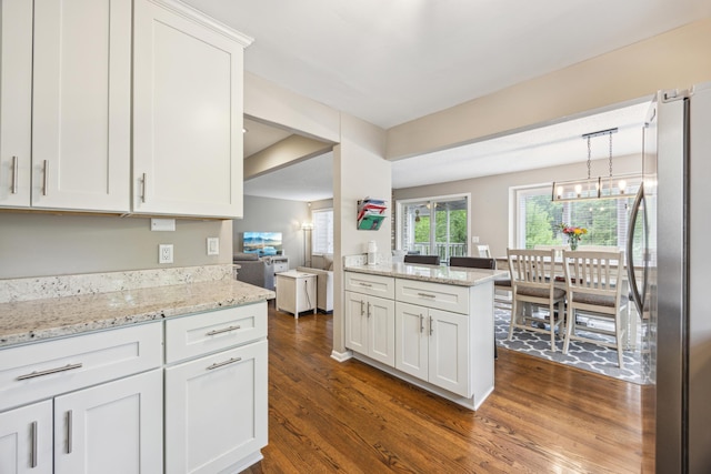 kitchen featuring freestanding refrigerator, dark wood-style flooring, white cabinetry, light stone counters, and pendant lighting