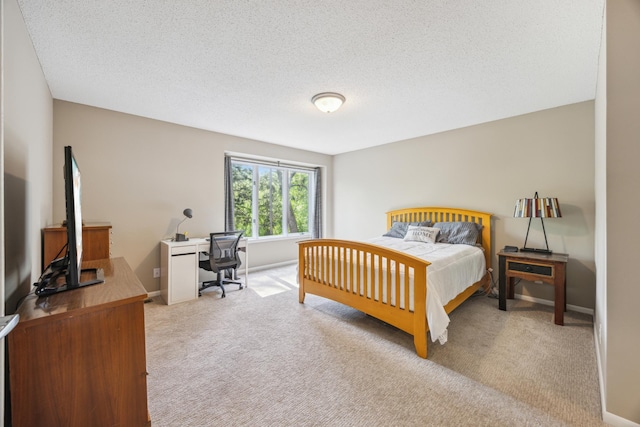 bedroom with carpet, an office area, a textured ceiling, and baseboards