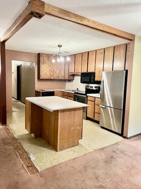 kitchen with stainless steel appliances, brown cabinets, light countertops, beam ceiling, and pendant lighting