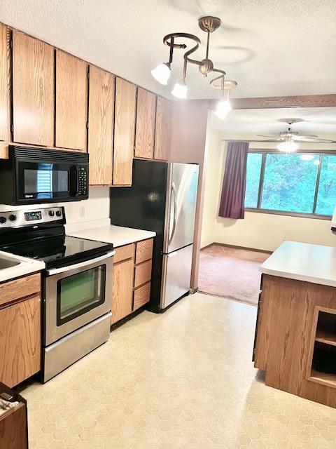 kitchen featuring stainless steel appliances, a textured ceiling, light countertops, a chandelier, and a ceiling fan