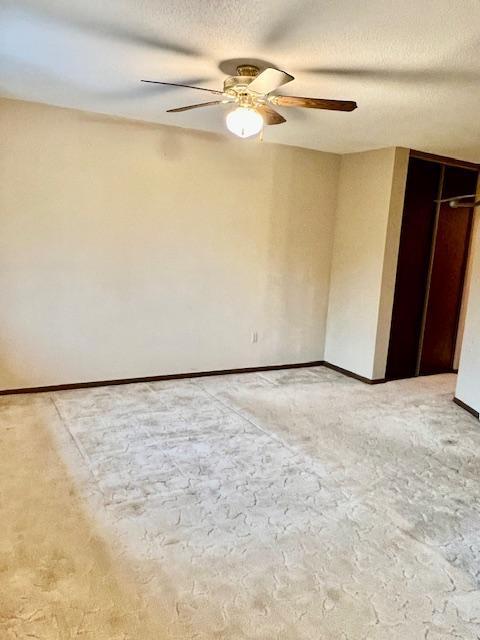 unfurnished bedroom featuring a ceiling fan, light colored carpet, and a textured ceiling