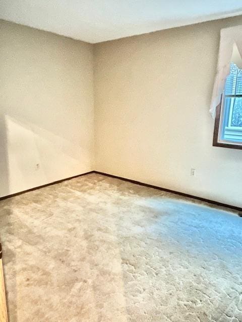 carpeted empty room featuring baseboards