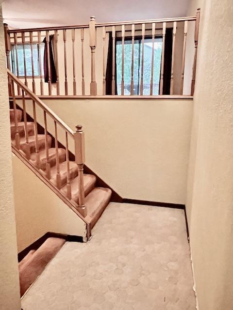 staircase featuring a textured wall and baseboards