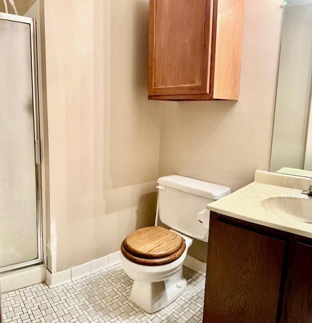 bathroom featuring a shower stall, toilet, vanity, and baseboards