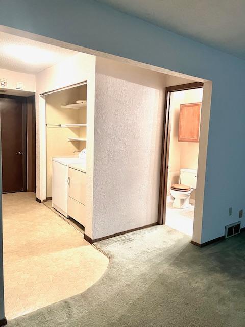 unfurnished bedroom with washing machine and clothes dryer, carpet, connected bathroom, and baseboards