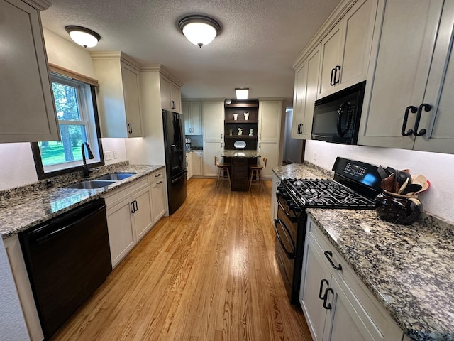 4220 23rd St NW, Willmar, MN 56201 - kitchen with black appliances, a sink, light wood finished floors, dark stone countertops, and open shelves
