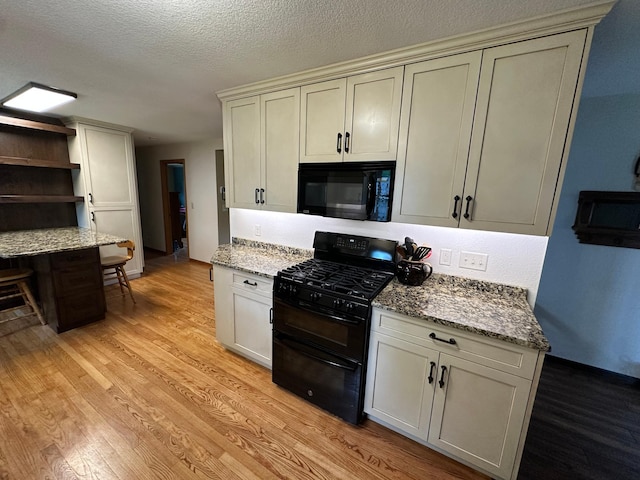 4220 23rd St NW, Willmar, MN 56201 - kitchen featuring black appliances, light wood-style floors, light stone counters, a textured ceiling, and open shelves