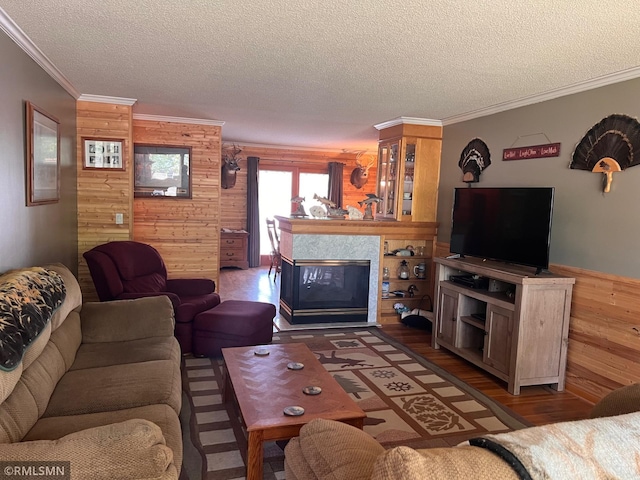 404 Clayborn Ave, Parkers Prairie, MN 56361 - living room featuring wooden walls, crown molding, a textured ceiling, a multi sided fireplace, and wood finished floors