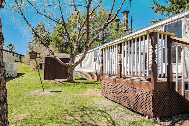 view of grassy yard with a storage unit, a deck, and an outbuilding