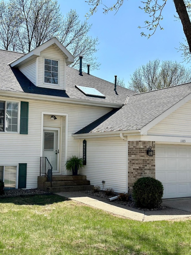 view of front facade with roof with shingles, a garage, a front yard, and brick siding