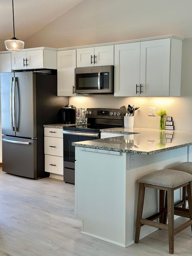 kitchen with stainless steel appliances, light wood-type flooring, white cabinets, a peninsula, and a kitchen breakfast bar