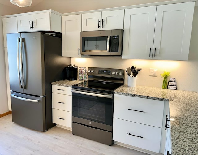 kitchen with appliances with stainless steel finishes, light wood finished floors, light stone countertops, and white cabinets