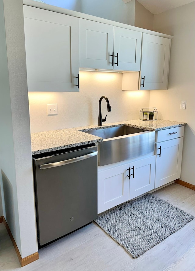 kitchen featuring dishwasher, a sink, light wood-style flooring, baseboards, and white cabinetry