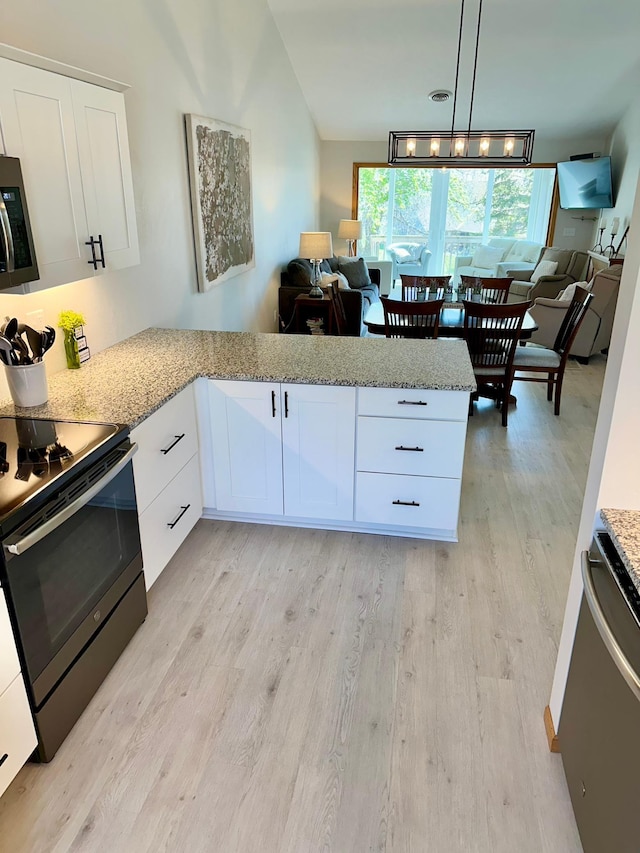 kitchen featuring stainless steel appliances, open floor plan, light wood-type flooring, lofted ceiling, and a peninsula