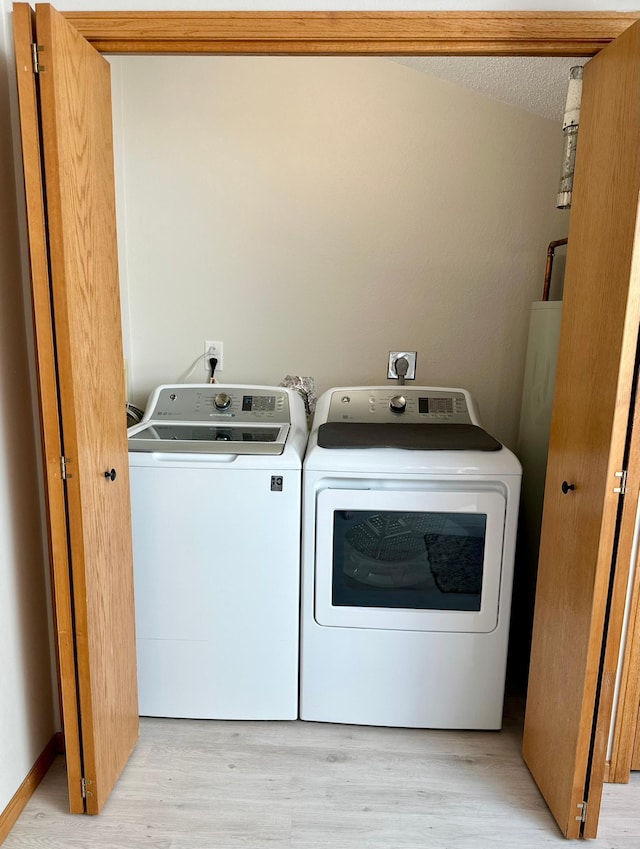 laundry room with washing machine and dryer and light wood-type flooring