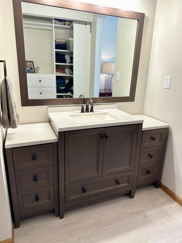 bathroom featuring wood finished floors, baseboards, and vanity
