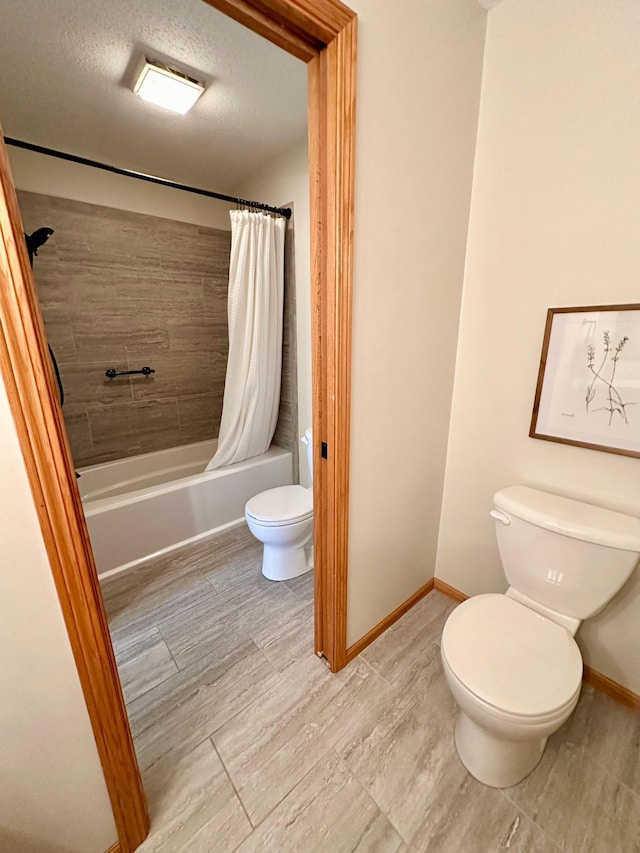 full bath featuring toilet, shower / tub combo with curtain, baseboards, and a textured ceiling
