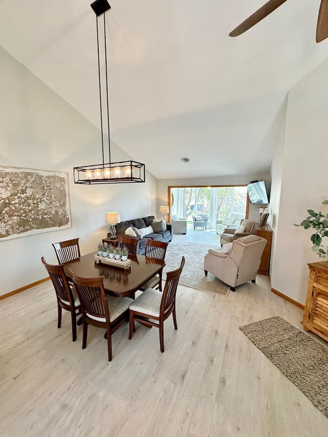 dining area featuring light wood-type flooring, a ceiling fan, baseboards, and lofted ceiling
