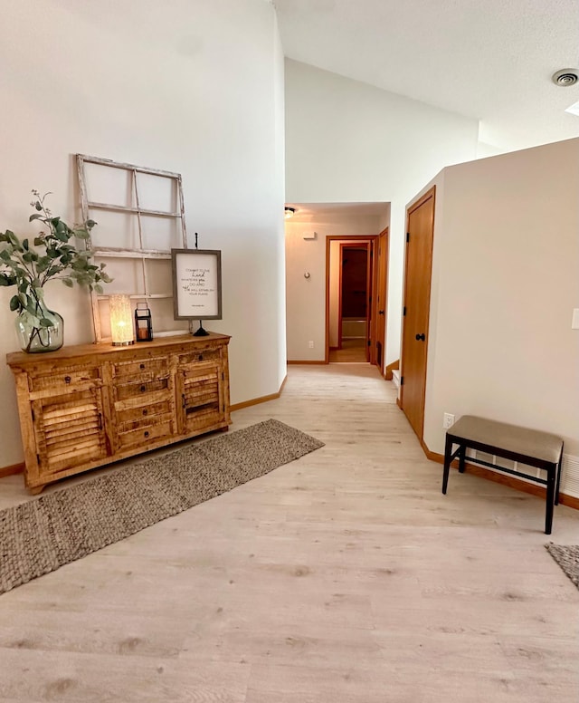 hall featuring high vaulted ceiling, baseboards, and wood finished floors