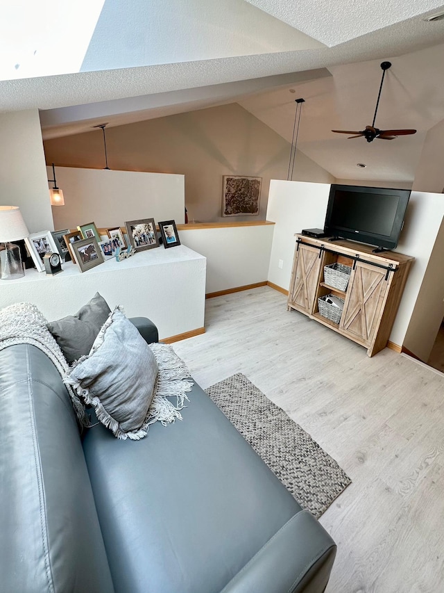 living room with wood finished floors, vaulted ceiling, ceiling fan, and baseboards