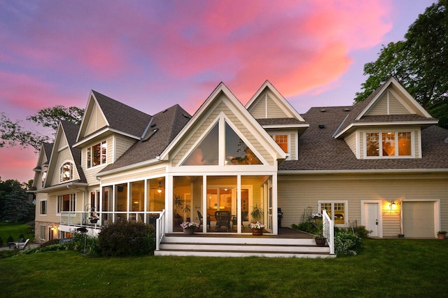rear view of house with a lawn, a shingled roof, and a sunroom