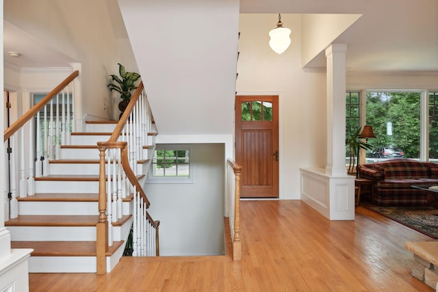 entryway with wood finished floors, decorative columns, and healthy amount of natural light