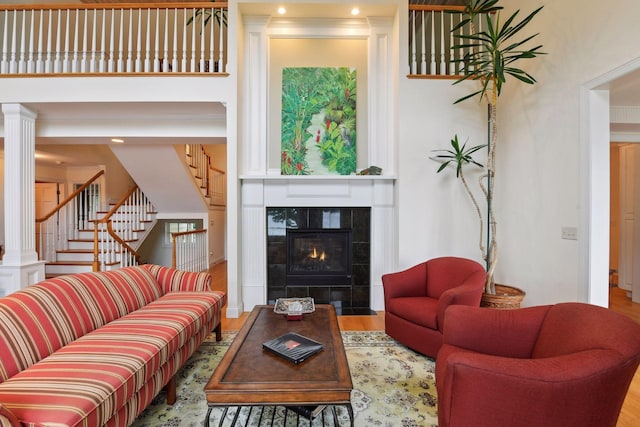 living room featuring stairway, a fireplace, wood finished floors, decorative columns, and recessed lighting