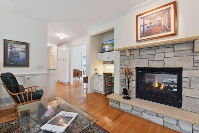 living area featuring crown molding, light wood finished floors, and a fireplace