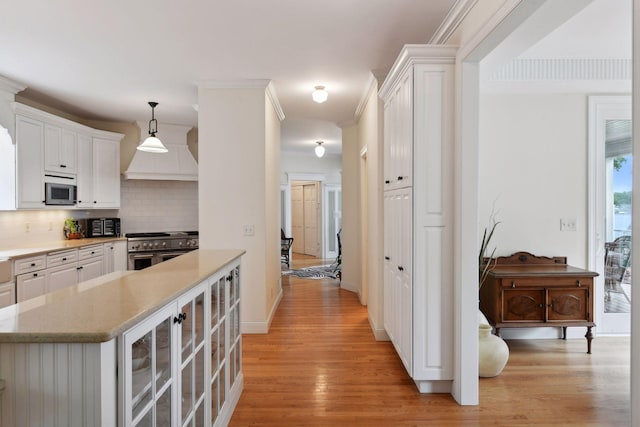 kitchen featuring appliances with stainless steel finishes, light wood-type flooring, decorative backsplash, white cabinetry, and baseboards