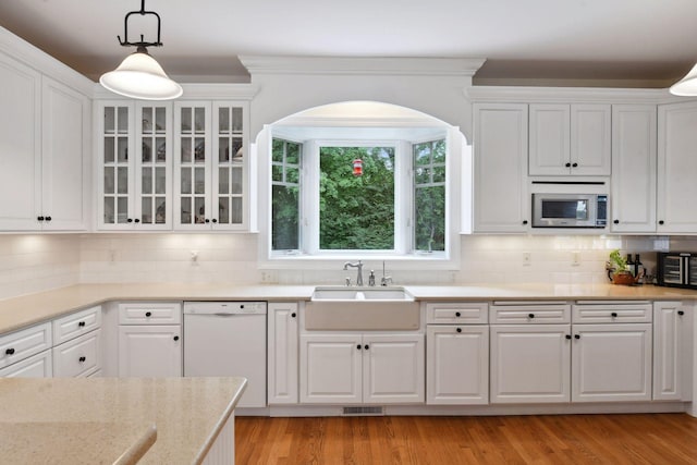 kitchen with dishwasher, stainless steel microwave, a sink, white cabinets, and pendant lighting