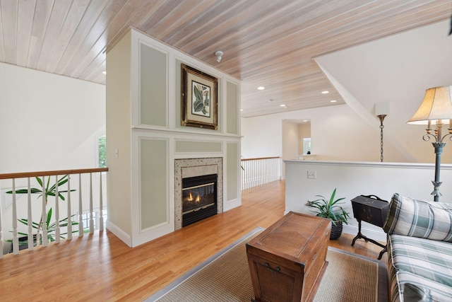 living area with wood ceiling, wood finished floors, a tiled fireplace, and recessed lighting