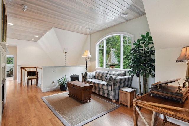 living area featuring light wood-type flooring, lofted ceiling, and baseboards