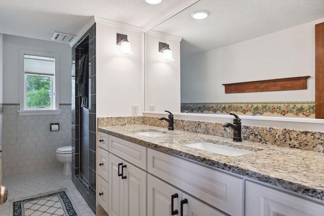 full bathroom featuring tile walls, double vanity, tile patterned floors, a shower, and wainscoting