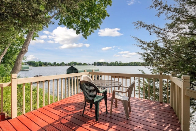 deck with a water view and outdoor dining area
