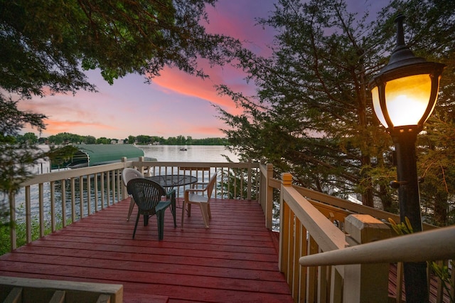 deck at dusk featuring a water view