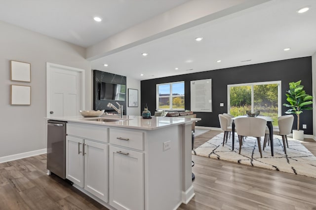 kitchen featuring a sink, dishwasher, white cabinets, wood finished floors, and light countertops