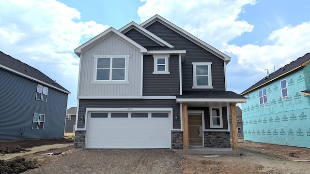 3900 Helmo Ave N, Oakdale, MN 55128 - view of front of property featuring stone siding, a garage, asphalt driveway, and board and batten siding