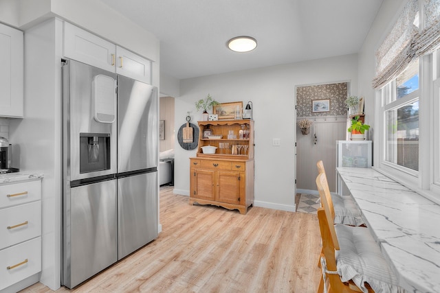 816 5th St S, Stillwater, MN 55082 - kitchen with stainless steel refrigerator with ice dispenser, white cabinetry, light countertops, baseboards, and light wood-style flooring