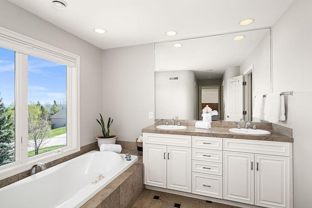 full bathroom featuring a tub, recessed lighting, and double vanity